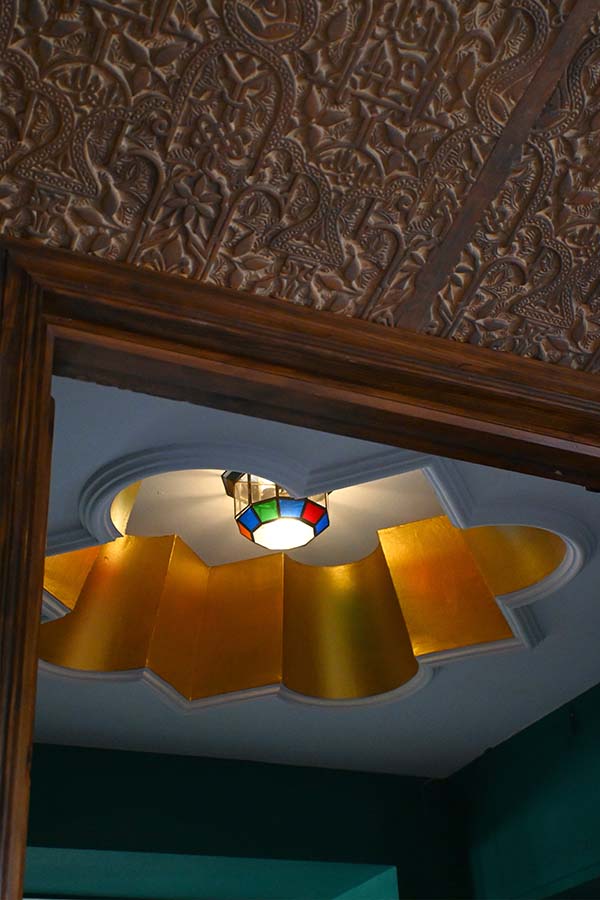 carved-wooden-ceiling-with-a-golden-alcove-and-stained-glass-lamp-highlighting-unique-castle-design