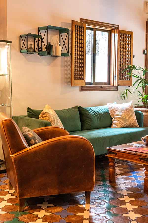 cozy-lounge-area-with-green-velvet-sofa-leather-armchair-and-patterned-tiles-at-hotel-castillo-de-monda-spain