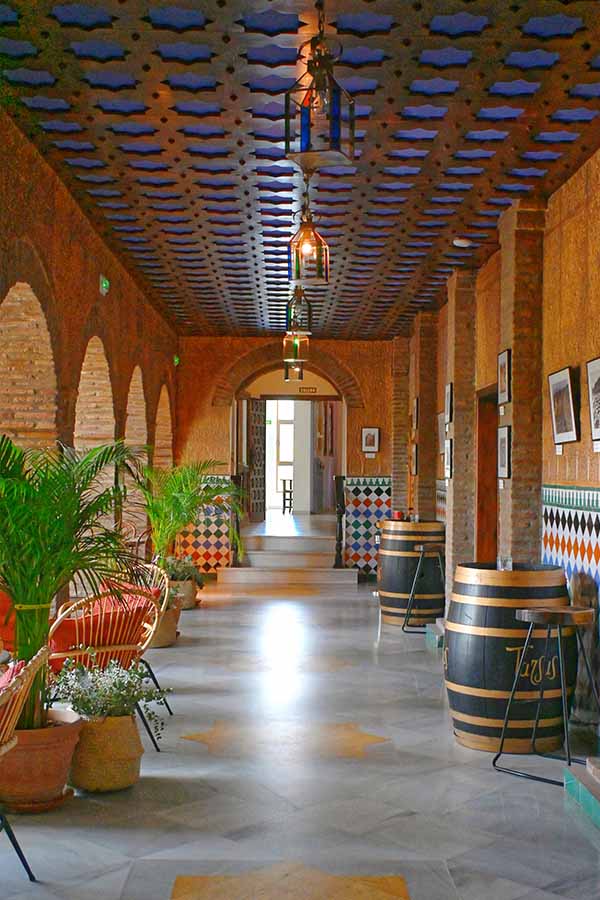 grand-arched-corridor-with-brick-columns-wine-barrels-and-ornate-blue-ceiling-at-hotel-castillo-de-monda-spain