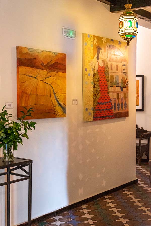 hallway-wall-decorated-with-colorful-spanish-paintings-and-hanging-lantern-at-hotel-castillo-de-monda-spain