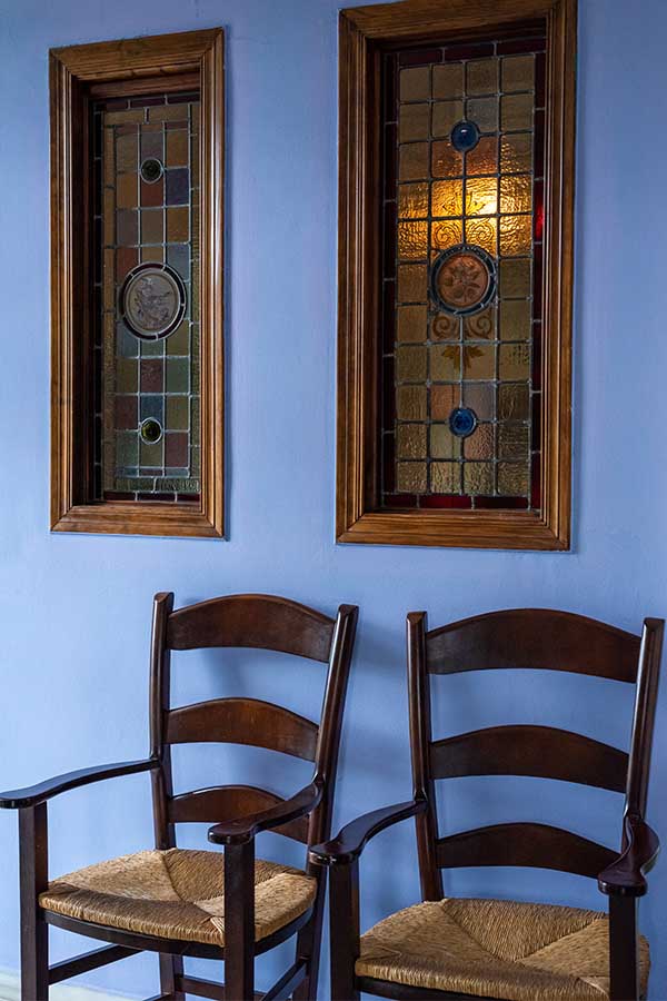 rustic-wooden-chairs-against-blue-wall-with-stained-glass-windows-providing-interior-design-inspiration