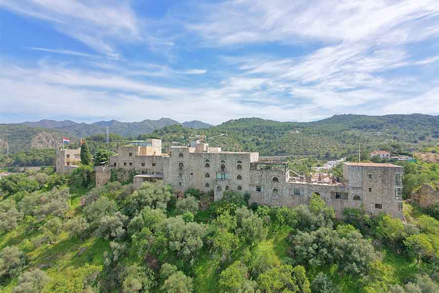 scenic-aerial-view-of-historic-stone-castle-nestled-in-green-hills-at-hotel-castillo-de-monda-spain