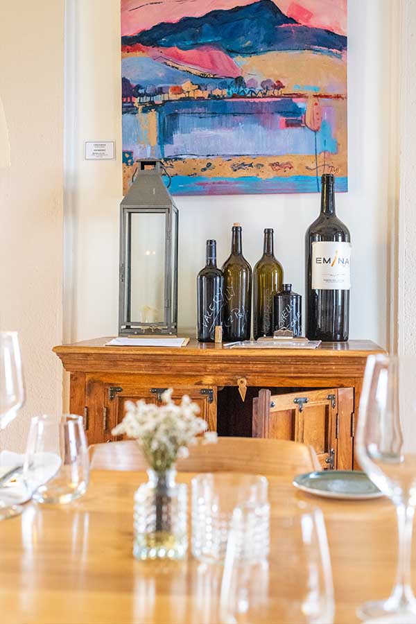 wooden-credenza-with-wine-bottles-and-vibrant-landscape-painting-showing-interior-design-inspiration