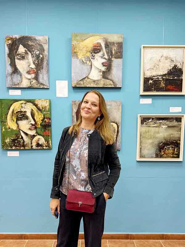 contemporary-art-mixed-media-art-woman-standing-in-front-of-an-art-gallery-wall-displaying-multiple-portrait-paintings