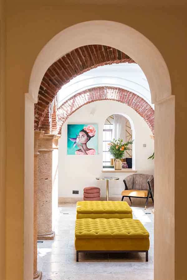 Courtyard-lounge-tufted-yellow-ottomans-brick-arches-hotel-claude-marbella-spain-boutique-hotel-design-interior-design