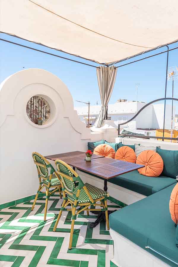 Outdoor-terrace-seating-area-green-banquette-orange-pillows-hotel-claude-marbella-spain-interior-design-boutique-hotel-design
