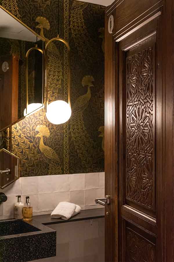 Powder-room-peacock-wallpaper-pendant-light-carved-wooden-door-hotel-claude-marbella-spain-interior-design-boutique-hotel-design