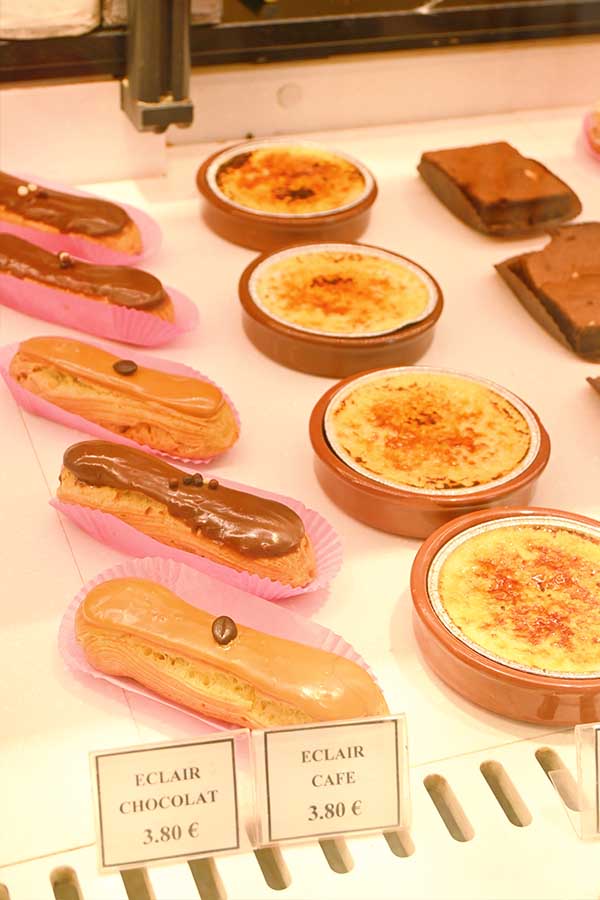 assortment-of-french-desserts-including-chocolate-and-coffee-eclairs-alongside-individual-creme-brulee-dishes-in-a-pastry-shop