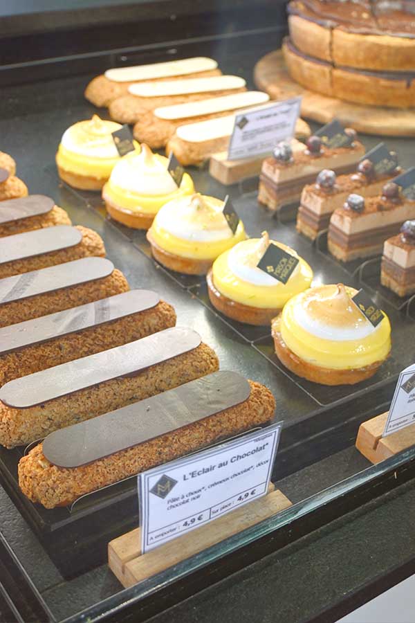 bakery-display-counter-filled-with-chocolate-eclairs-lemon-meringue-tarts-and-layered-pastries