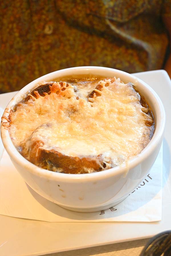 classic-parisian-french-onion-soup-topped-with-a-thick-layer-of-melted-golden-crusted-cheese-and-toasted-bread-served-in-a-white-bowl