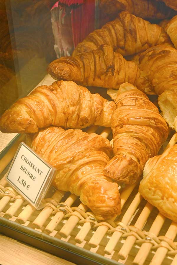 freshly-baked-golden-butter-croissants-displayed-on-a-wooden-rack-inside-a-french-bakery-display-case-in-paris