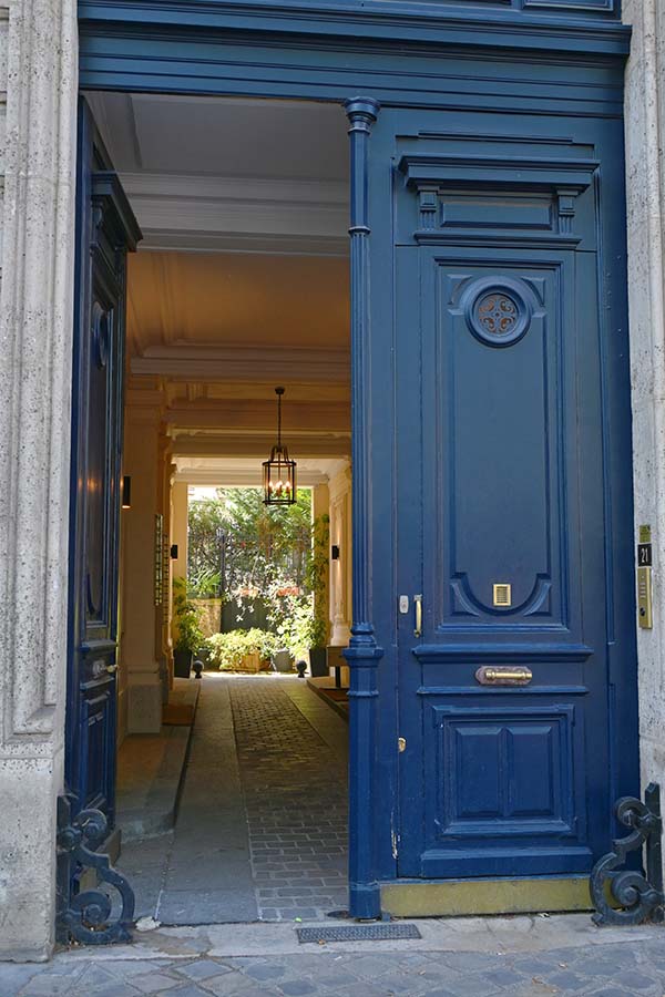 paris-france-open-blue-wooden-door-leading-to-a-sunlit-courtyard-passage