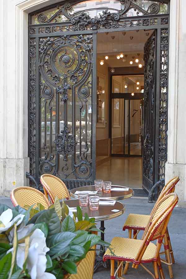 paris-france-outdoor-cafe-tables-in-front-of-an-ornate-wrought-iron-glass-doorway