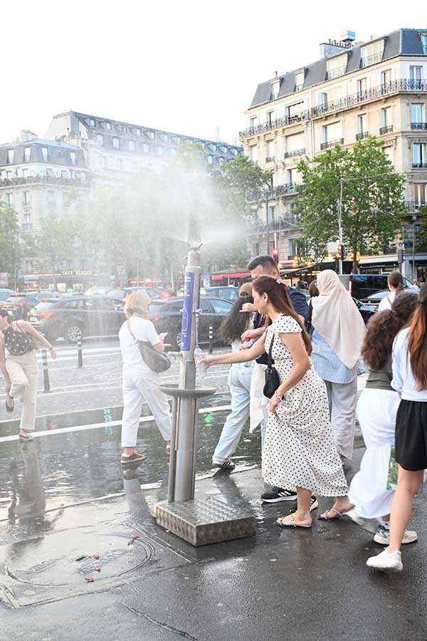 paris-france-pedestrians-filling-water-bottles-and-cooling-off-at-a-public-misting-fountain