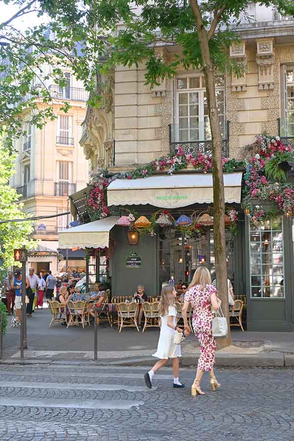 paris-france-people-walking-past-a-charming-corner-cafe-decorated-with-lush-pink-flowers