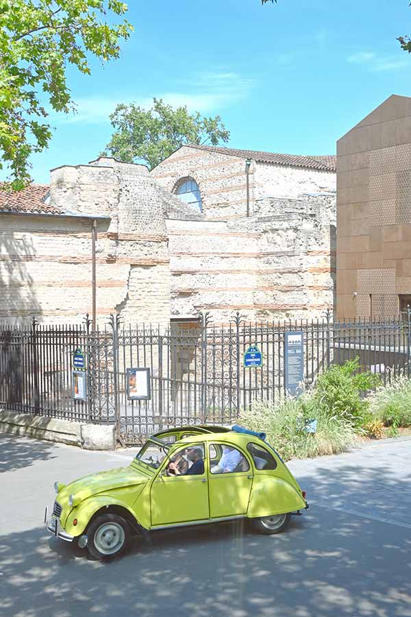 paris-france-yellow-vintage-citroen-2cv-car-driving-past-the-cluny-museum-roman-baths