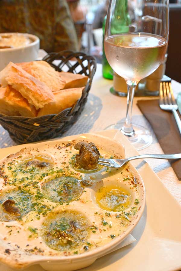 traditional-dish-of-escargot-cooked-in-garlic-herb-butter-served-with-a-basket-of-crusty-bread-and-a-glass-of-rose-wine-in-paris