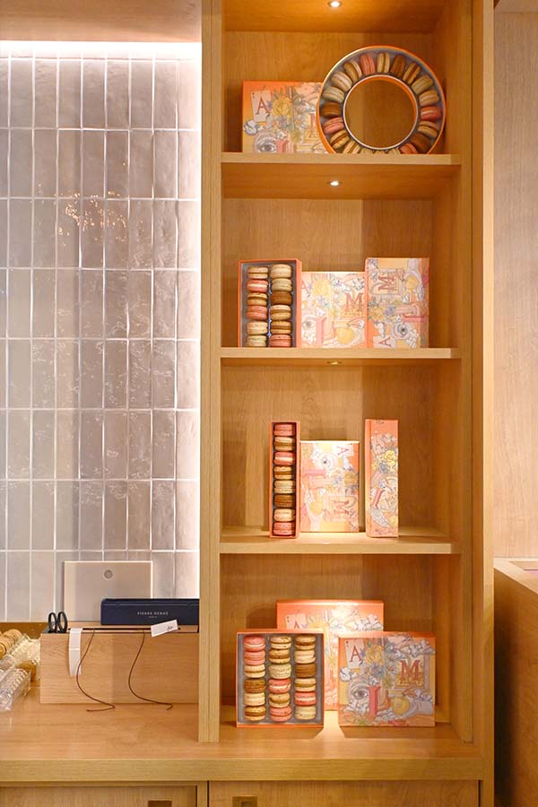 wooden-shelves-displaying-elegantly-packaged-boxes-of-french-macarons-in-a-paris-boutique