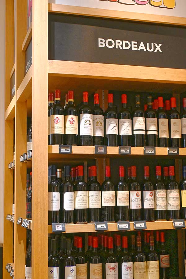 wooden-shelves-stocked-with-french-bordeaux-red-wines-in-a-paris-wine-shop