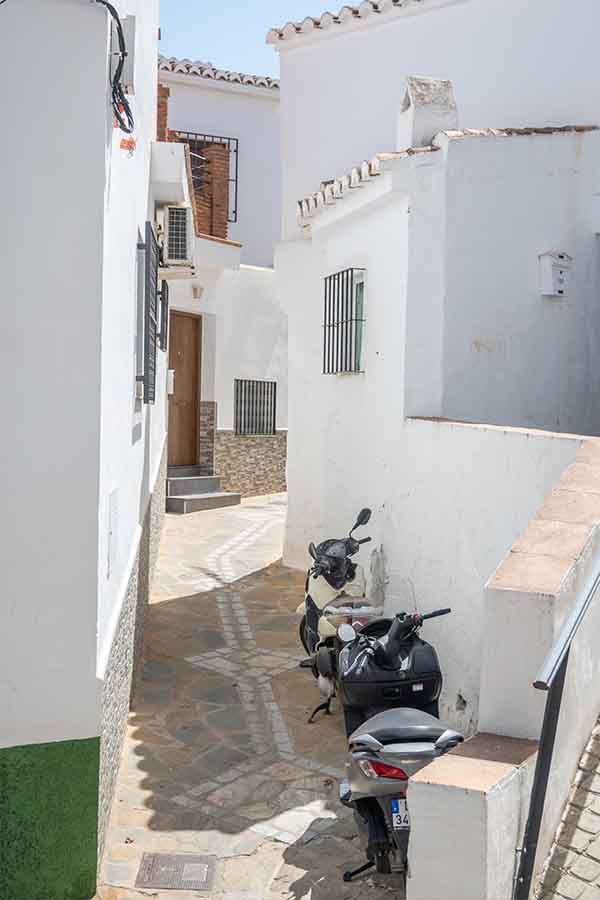 narrow-whitewashed-alleyway-parked-motorcycles-Almachar-Spain-white-villages-Andalusia