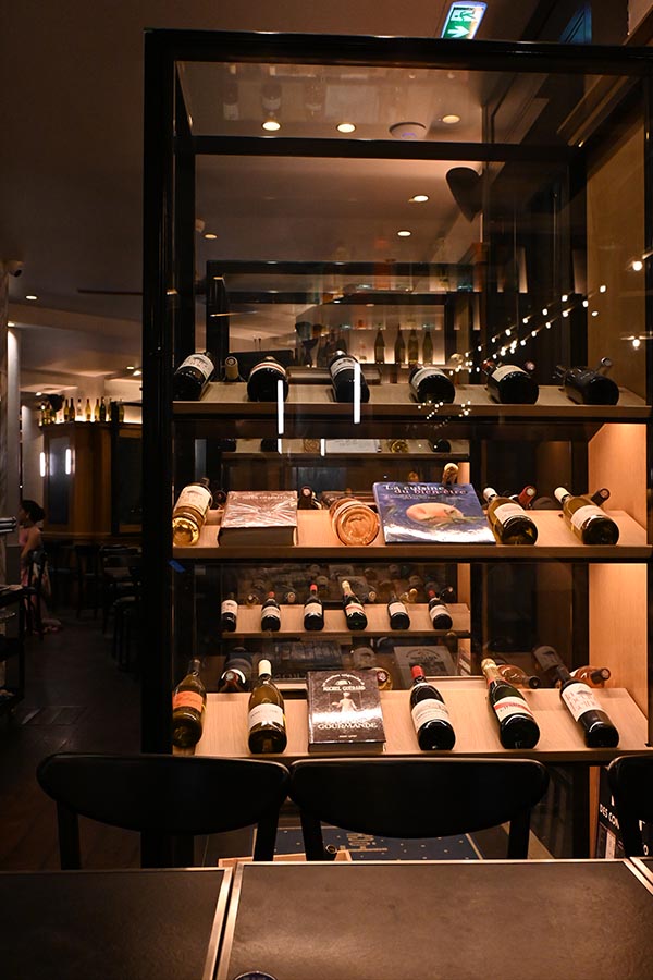 night-photography-display-case-filled-with-wine-bottles-and-books-inside-a-restaurant