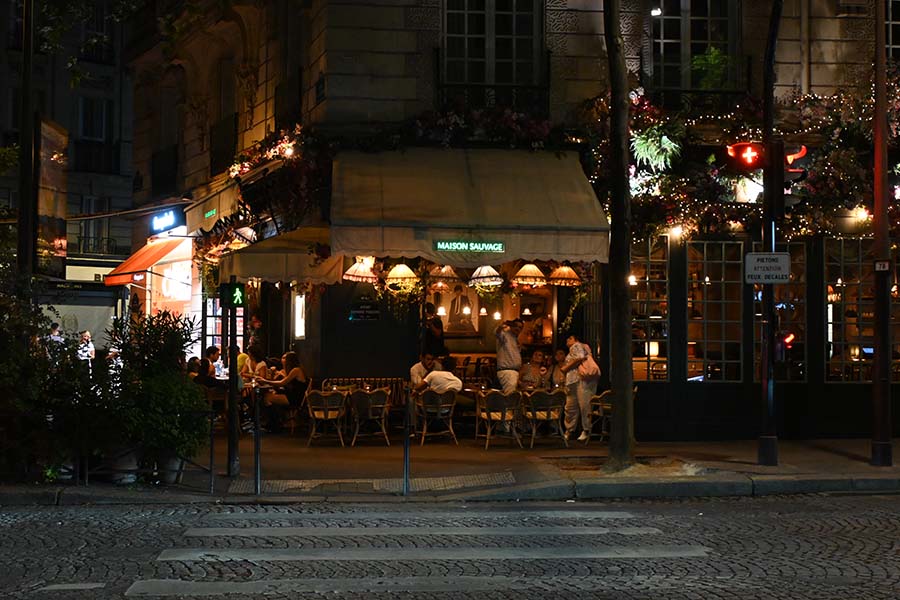 paris-at-night-a-charming-corner-cafe-adorned-with-lush-greenery-and-glowing-lamps