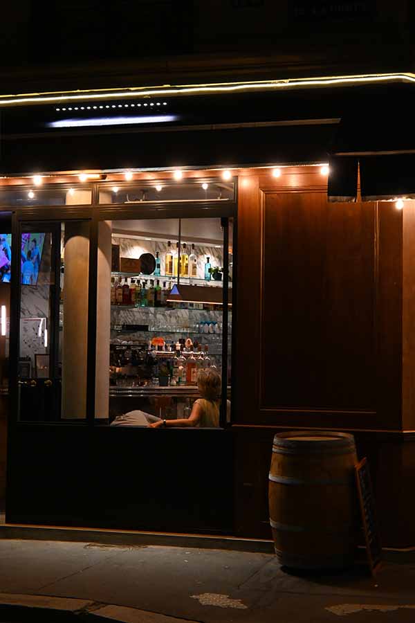paris-at-night-view-of-a-cozy-bar-window-with-a-wine-barrel-outside-on-the-sidewalk