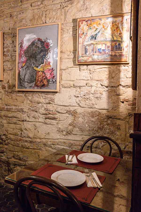 rustic-dining-table-set-against-an-exposed-stone-wall-with-paintings-offering-vintage-travel